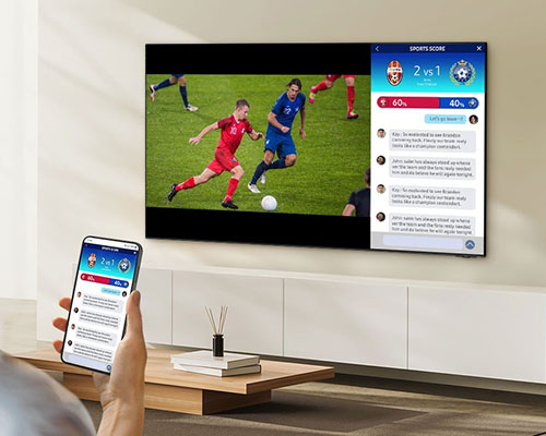 A person watches 2 different screens on their TV simultaneously. They have one screen displaying a soccer match and the second screen mirroring their mobile with live stats.