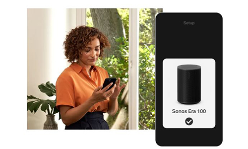 Woman leaning on a credenza using her phone to control a black Sonos Era 300