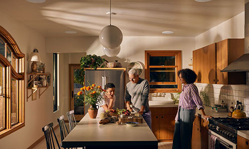 Family in the kitchen with Sonance in-ceiling speakers installed over an island