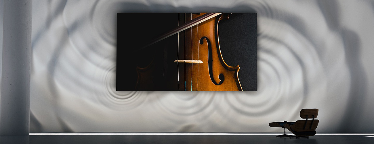 MICRO LED TV is wall-mounted and showing a closeup of a violin. The wall behind the MICRO LED shows large wave ripple graphics.